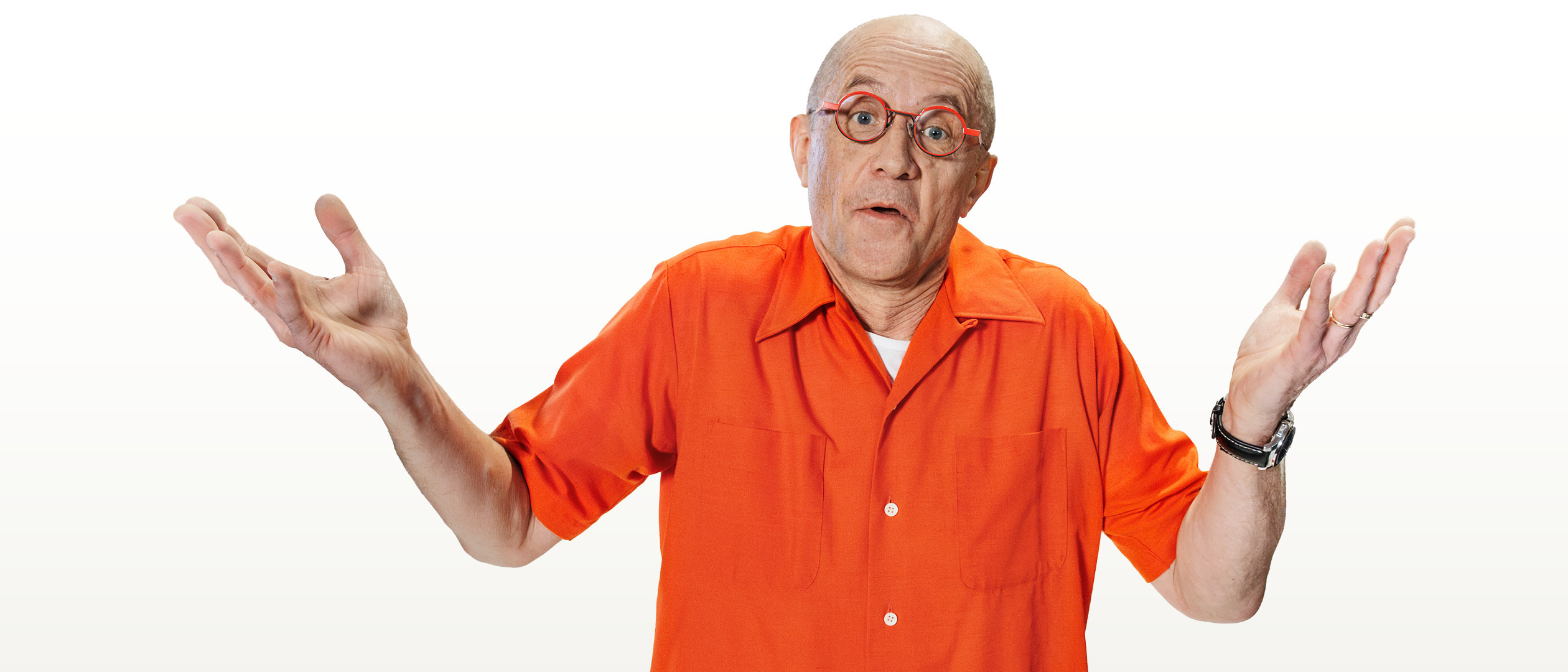 En man klädd o orange skjorta ser frågande ut med armarna lyfta.